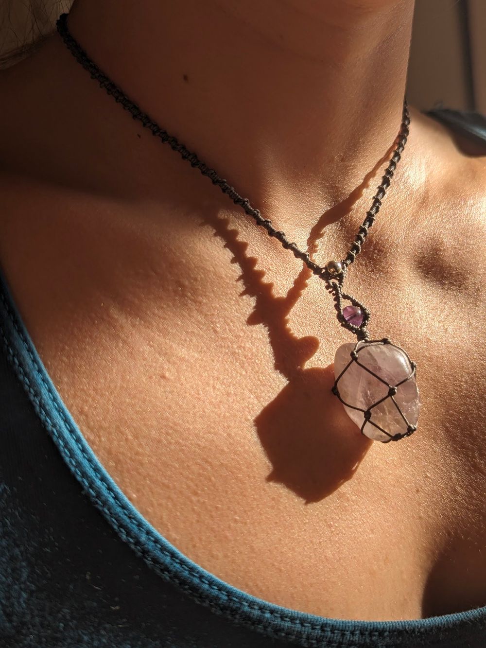 Pendentif en cristal de roche serti de macramé, porté, dans la lumière du soir